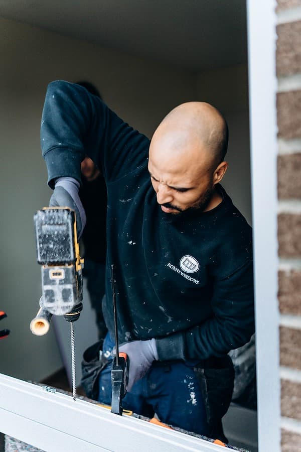 Menuisier Ronny Windows en train de percer pour l'installation d'un châssis